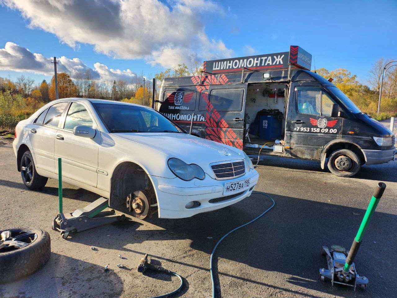 Белый Mercedes C-Class на домкрате после попадания в яму, рядом фургон выездного шиномонтажа TireMasters